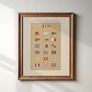 May include: A framed print titled Commercial Code of Signals featuring a grid of colorful nautical signal flags on a tan background. The artwork is encased in a dark brown wooden frame with a visible grain texture, displaying various geometric flag designs.