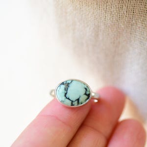 May include: A silver ring with a light blue oval turquoise stone set in a bezel setting.
