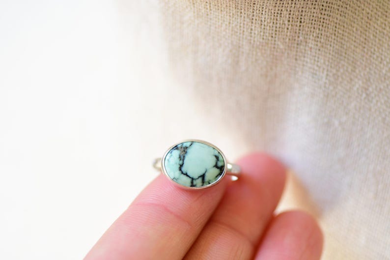 May include: A silver ring with a light blue oval turquoise stone set in a bezel setting.