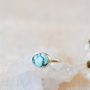 May include: A silver ring with a light blue turquoise stone set in a bezel setting.