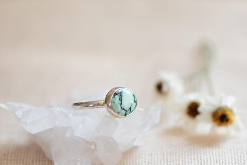 May include: A silver ring with a round, green and black turquoise stone.