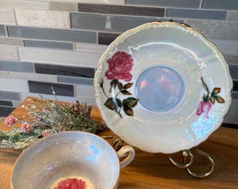 May include: A vintage teacup and saucer set with a pearl iridescent glaze. The set features a pink rose floral design.