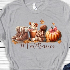 May include: A gray t-shirt with a graphic design of fall-themed items, including boots, a coffee cup, a knitted hat, and a pumpkin. The text "#FallBasics" is printed below the graphic.
