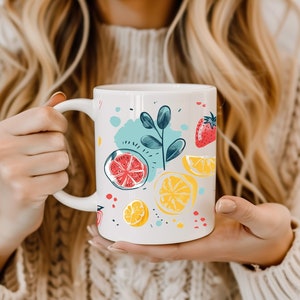 Puede incluir: Taza de cerámica blanca con un diseño colorido de limones, limas y fresas. El diseño está dibujado a mano y presenta un fondo azul claro con acentos blancos y amarillos.