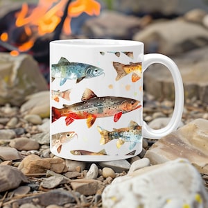 May include: White ceramic mug with a colorful watercolor design of various fish. The fish are in shades of blue, green, orange, and red.