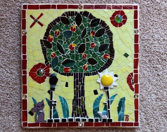 May include: A mosaic artwork depicting a green tree with red flowers, a yellow flower, a purple cat, and two black lampposts on a yellow background. The artwork is framed with a red border.