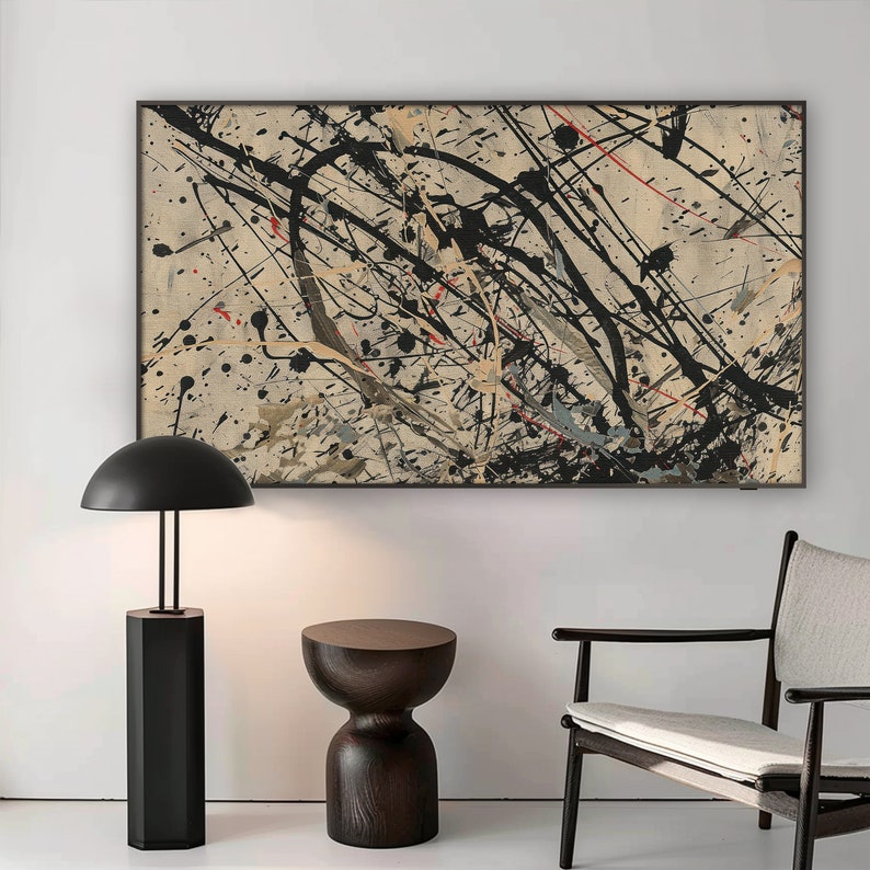 Pu&ograve; includere: Un dipinto astratto in bianco e nero con schizzi di rosso e giallo su uno sfondo beige. Il dipinto &egrave; incorniciato in nero e appeso a una parete bianca. Una lampada nera con un paralume a cupola e un tavolino in legno scuro sono in primo piano.
