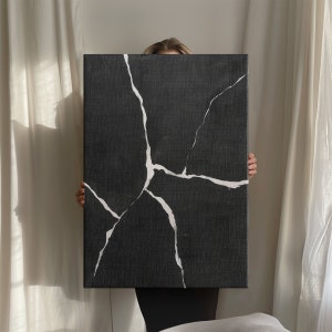 May include: A black canvas painting with white crackle lines. The canvas is textured and has a modern abstract design.