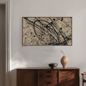 Pu&ograve; includere: Stampa d'arte astratta in una cornice marrone con schizzi di vernice nera, bianca e rossa su uno sfondo beige.