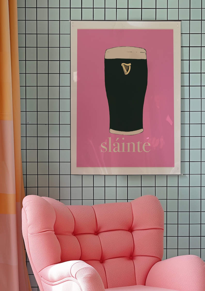 May include: A pink poster with a black and white illustration of a pint of Guinness. The poster has the word "sl&aacute;inte" written in white at the bottom.