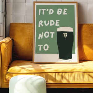May include: A framed print with a green background and white text that reads "It'd be rude not to". A glass of dark beer with a white head is pictured to the right of the text.
