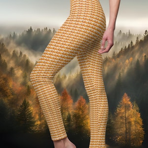 May include: Leggings with a repeating pattern of orange foxes on a white background. The leggings are form-fitting and reach the ankles. The background is a scenic view of a forest with a road.