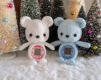 May include: Two crochet bear-shaped plush toys, one white and one light blue, each with a screen in their belly. The white bear has a pink screen border, and the blue bear has a blue screen border. Both have black eyes and pink cheeks.