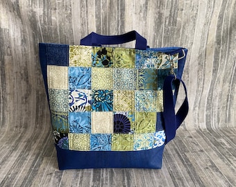 May include: A large blue tote bag with a patchwork design of blue, green and white squares. The bag has a long blue strap and a top handle.