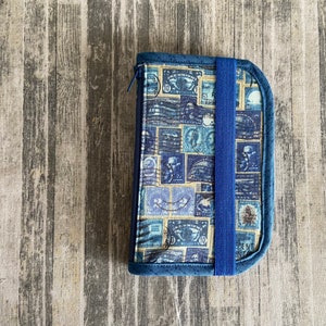 May include: A blue zippered pouch with a vintage stamp print and a blue elastic strap closure.
