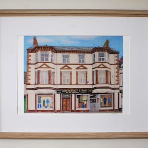 Peut inclure: Une illustration dessinée à la main d'un immeuble de trois étages avec une vitrine. Le bâtiment est peint dans des tons de blanc, de brun et de rouge. La vitrine porte une enseigne qui indique "John Moffat & Sons, The Mayfair Tailors".