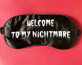 May include: Black sleep mask with white text that reads "Welcome to my nightmare".