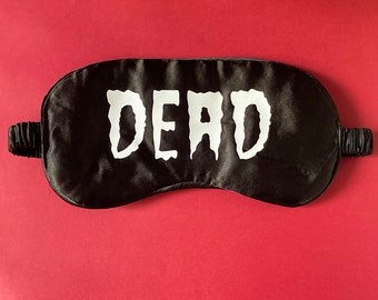 May include: Black sleep mask with the word "DEAD" printed in white.