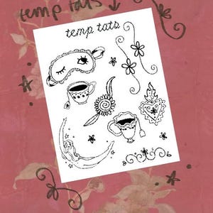 Op de afbeelding: Een wit vel met tijdelijke tatoeages met zwarte lijntekeningen van een slaapmasker, twee theekopjes, een maansikkel met een figuur, een heilig hart, bloemen en decoratieve krullen. De tekst temp tats staat bovenaan afgedrukt.