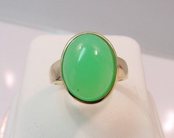 May include: A gold ring with a large, oval-shaped green gemstone.
