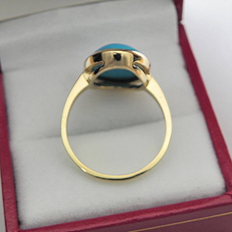 May include: A gold ring with a turquoise gemstone set in a bezel setting. The ring is in a red velvet ring box.