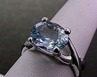 May include: A silver ring with a light blue oval aquamarine gemstone. The ring has a twisted band.