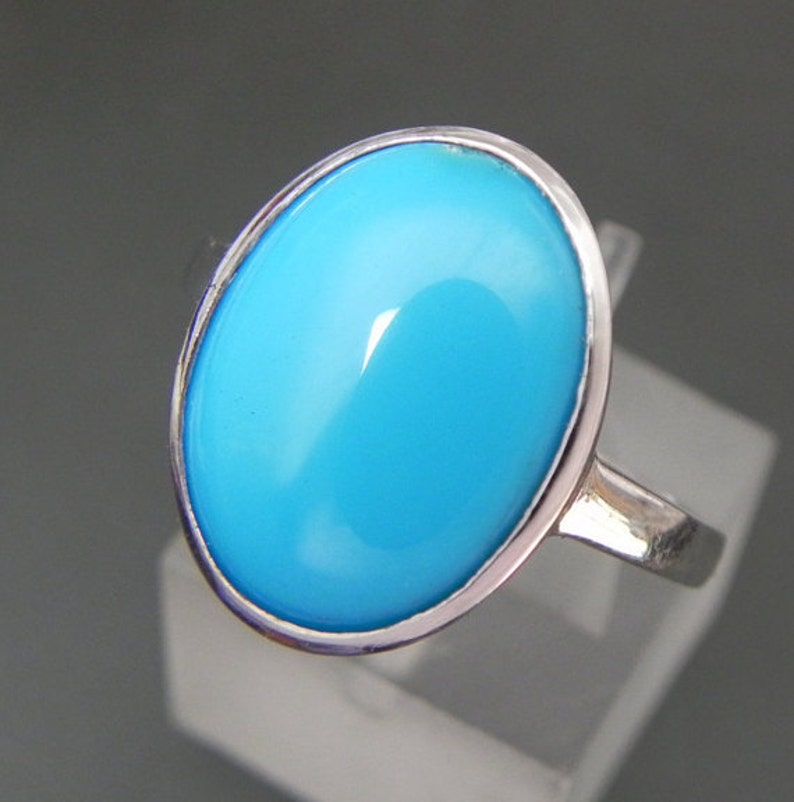 May include: A silver ring with a large oval turquoise gemstone.