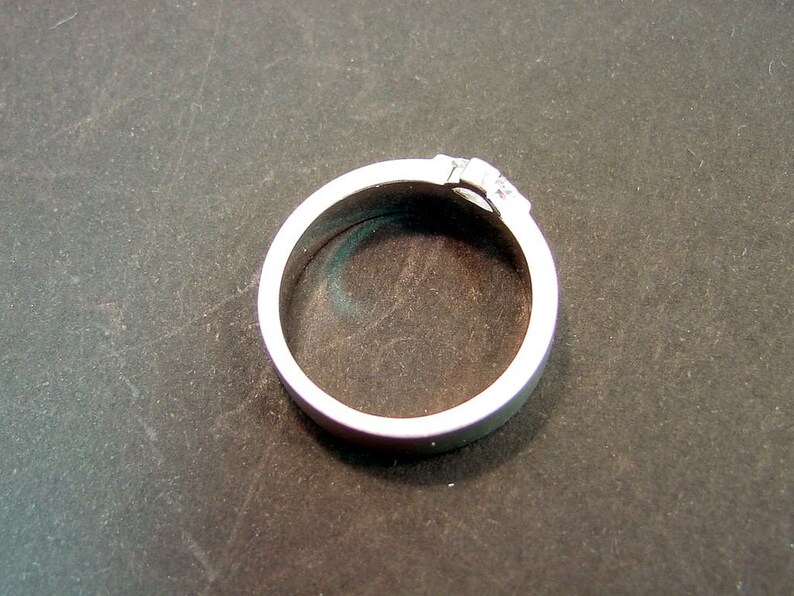 May include: A silver ring with a small, clear stone set in the band.