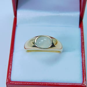 K&ouml;nnte beinhalten: Ein goldener Ring mit einem wei&szlig;en Edelstein in der Mitte. Der Ring befindet sich in einer roten Samtbox.