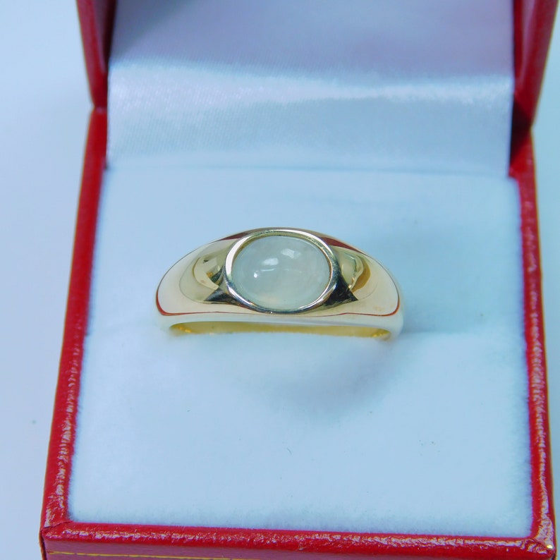 K&ouml;nnte beinhalten: Ein goldener Ring mit einem wei&szlig;en Edelstein in der Mitte. Der Ring befindet sich in einer roten Samtbox.