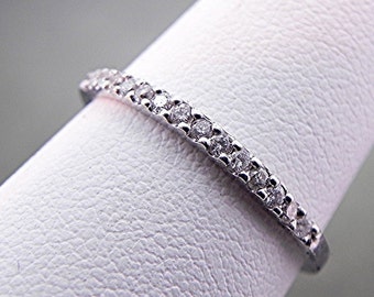 May include: A thin silver band with a row of small diamonds set in a pave setting.