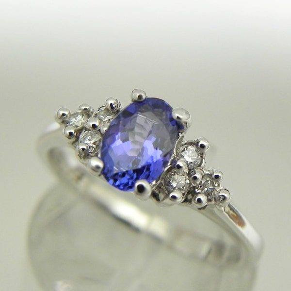 May include: A silver ring featuring a large oval blue gemstone surrounded by smaller white gemstones.