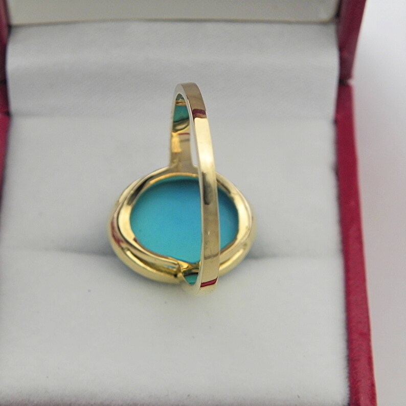 May include: A gold ring with a turquoise blue oval stone set in a bezel setting.