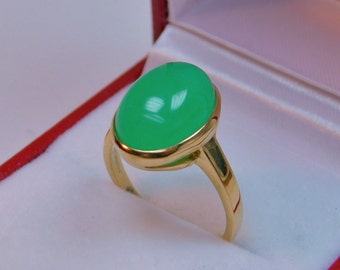 May include: A gold ring with a large, oval-shaped green gemstone. The ring is in a red and white jewelry box.