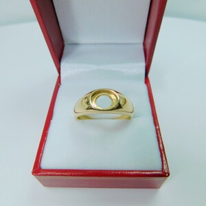 K&ouml;nnte beinhalten: Ein goldener Ring mit einer runden, leeren Fassung. Der Ring befindet sich in einer roten Schachtel.