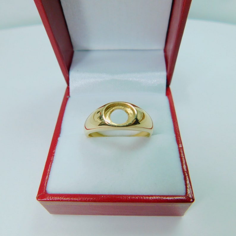 K&ouml;nnte beinhalten: Ein goldener Ring mit einer runden, leeren Fassung. Der Ring befindet sich in einer roten Schachtel.