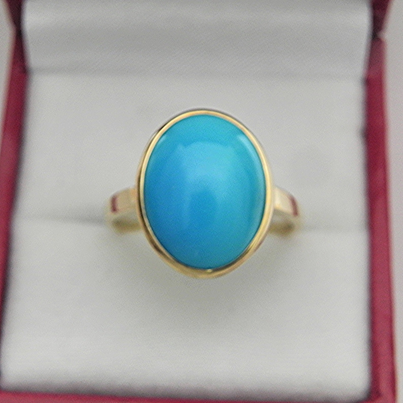 May include: A gold ring with a large oval turquoise gemstone.