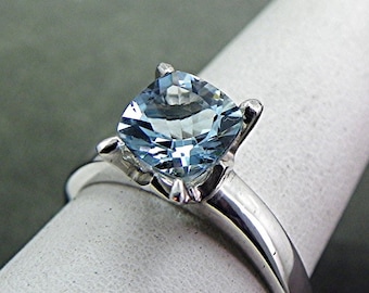 May include: A silver ring with a light blue cushion-cut gemstone.