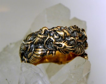 May include: A gold-toned ring featuring a detailed dragon design. The dragon's head is prominent, with intricate scales and a fierce expression.