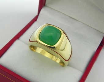May include: A gold ring with a green gemstone set in a square bezel. The ring is in a red velvet box.