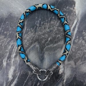 Collana a serpente con perline blu e chiusura a serpente decorata color argento.
