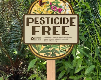 Op de afbeelding: Een rond tuinbord op een houten paal met de tekst PESTICIDE FREE. Het ontwerp bevat illustraties van een vlinder, bloemen en insecten. Het toont het logo van de Xerces Society en de tekst: Cultivating a home for insects that pollinate plants, eat pests and enrich our world. Join in at Xerces.org.