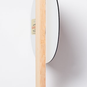 May include: A white round sign with a black border attached to a wooden stake. The sign has a gold sticker with the text "Outdoor Garden Display" on it.