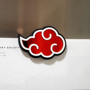 May include: A red and white cloud-shaped sticker with a black outline. The sticker is on a silver surface.