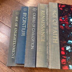 May include: A collection of hardcover books titled "Great Ages of Man" are displayed. The spines are in various shades of blue and gray, with gold lettering. Titles include "Age of Enlightenment," "Byzantium," and "Renaissance."