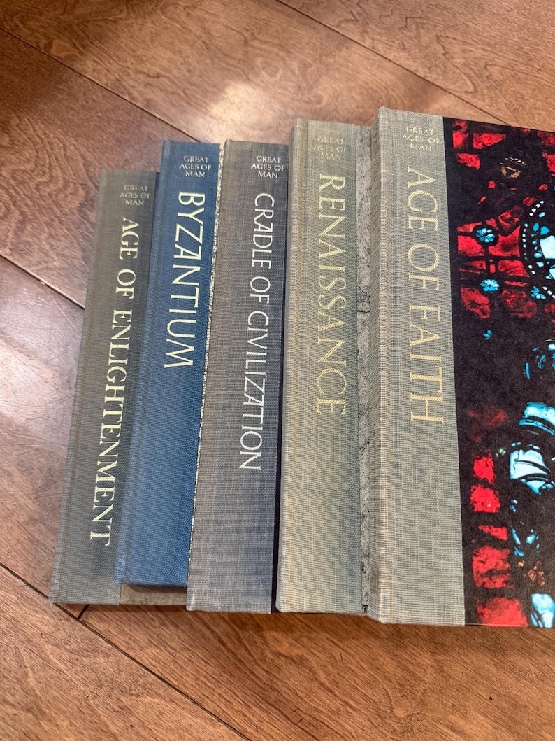 May include: A collection of hardcover books titled "Great Ages of Man" are displayed. The spines are in various shades of blue and gray, with gold lettering. Titles include "Age of Enlightenment," "Byzantium," and "Renaissance."
