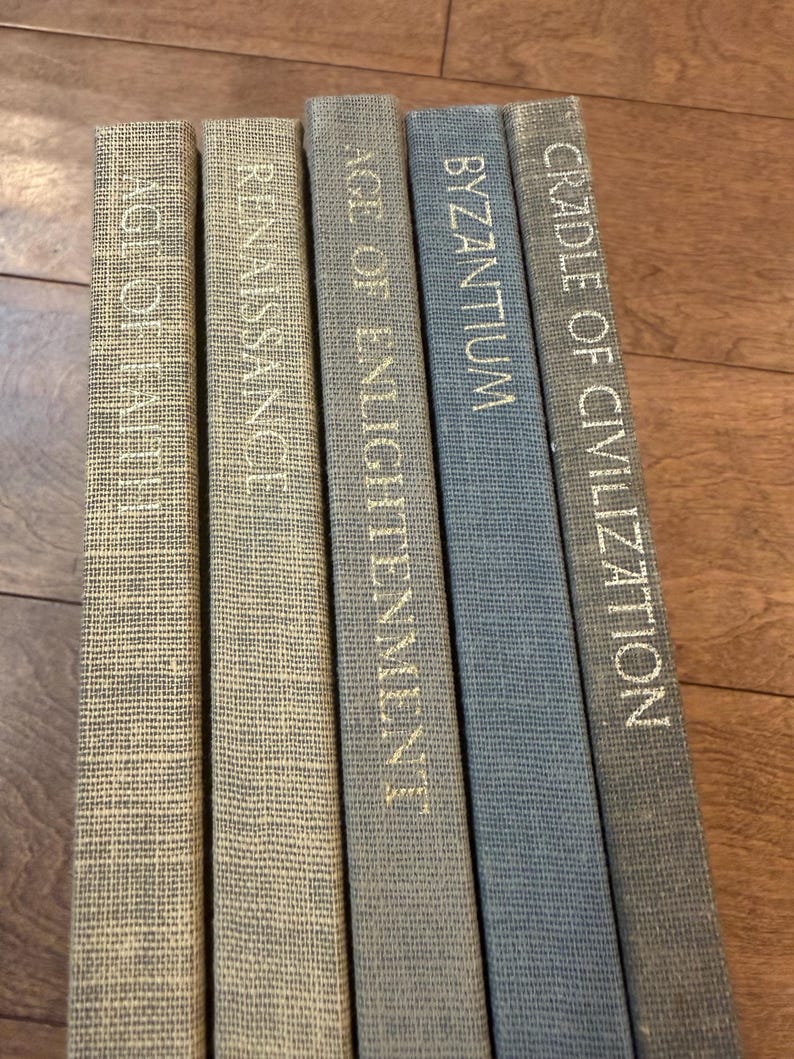 May include: A collection of five hardcover books with titles in gold lettering: "Age of Faith," "Renaissance," "Age of Enlightenment," "Byzantium," and "Cradle of Civilization." The books have textured covers in shades of beige and blue.