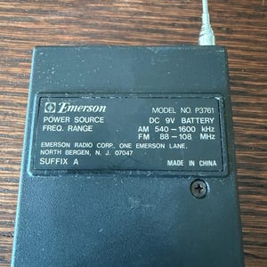 May include: Black Emerson radio with a silver antenna. The radio has the following text: "POWER SOURCE", "FREQ. RANGE", "MODEL NO. P3761", "DC 9V BATTERY", "AM 540-1600 kHz", "FM 88-108 MHz", "MADE IN CHINA".
