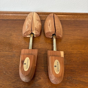 May include: Two wooden shoe trees with a light brown finish. Each tree has a rounded toe and heel, connected by a brass-colored metal rod. The label "NORDSTROM" is visible on the front of each tree.