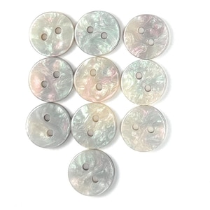 May include: A collection of ten round, iridescent buttons with two holes each. The buttons have a pearlescent sheen with hints of pink, green, and white. They are arranged on a white background, showcasing their decorative and functional design.